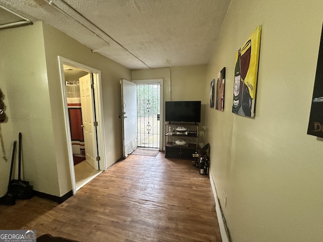 hallway with baseboards, wood finished floors, and a textured ceiling