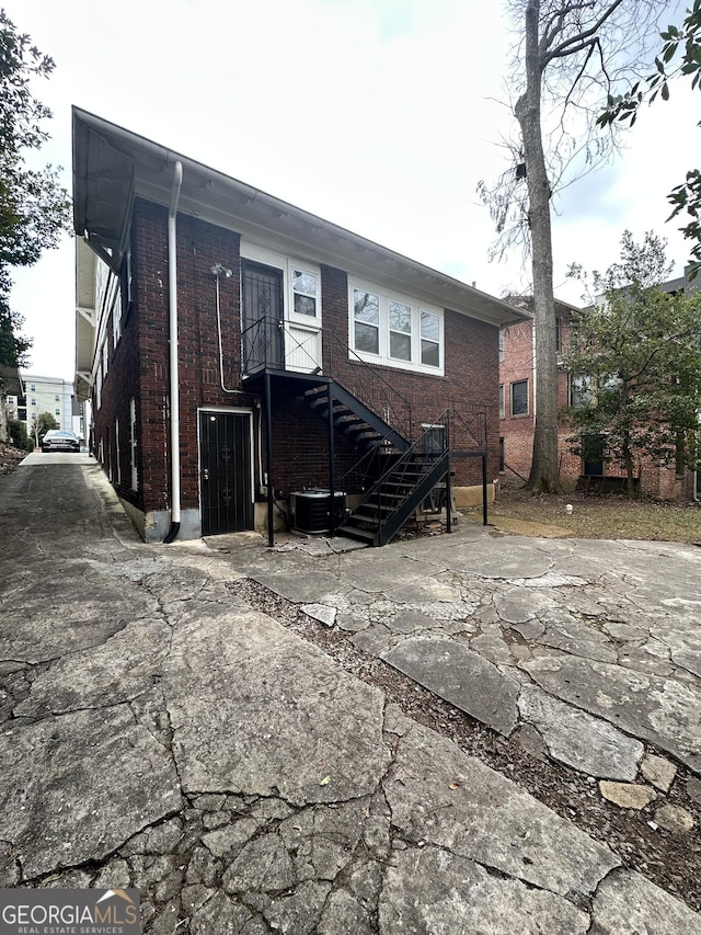 back of property featuring central air condition unit and brick siding