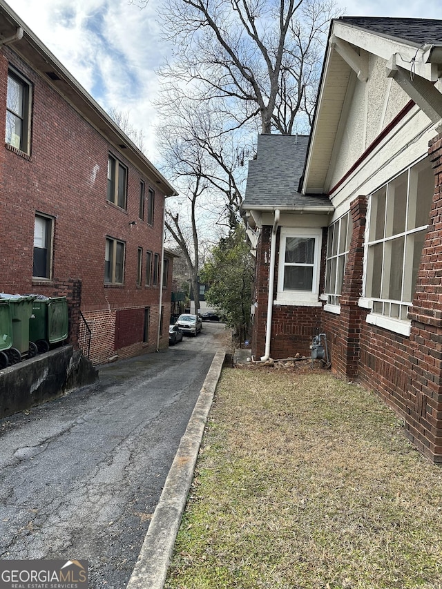 view of property exterior with a shingled roof and brick siding