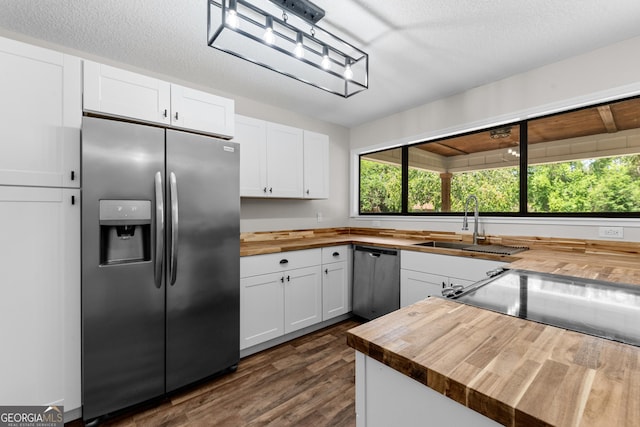 kitchen with wood counters, white cabinets, dark wood-style floors, and appliances with stainless steel finishes