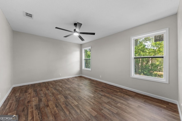 spare room with visible vents, dark wood-style flooring, ceiling fan, and baseboards