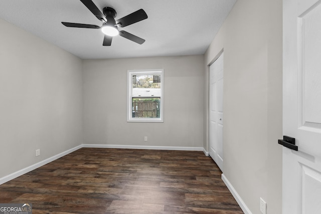 unfurnished bedroom featuring baseboards, dark wood-style flooring, and a closet