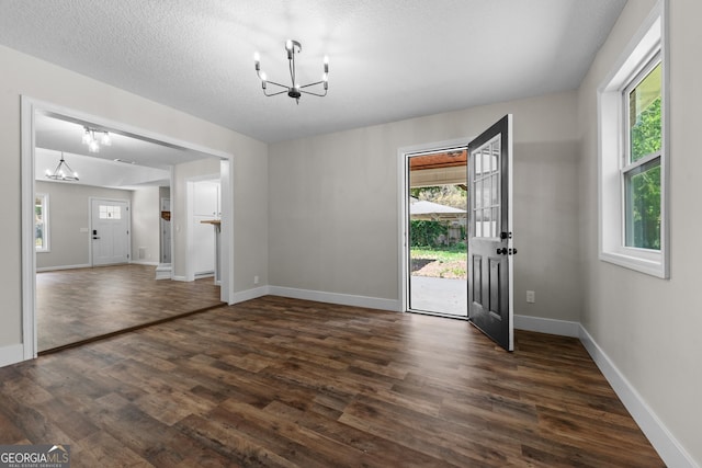 entryway with an inviting chandelier, dark wood-style flooring, and baseboards