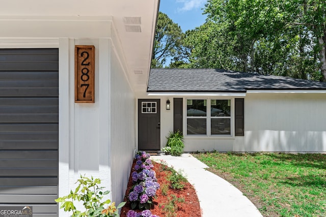 view of exterior entry featuring roof with shingles