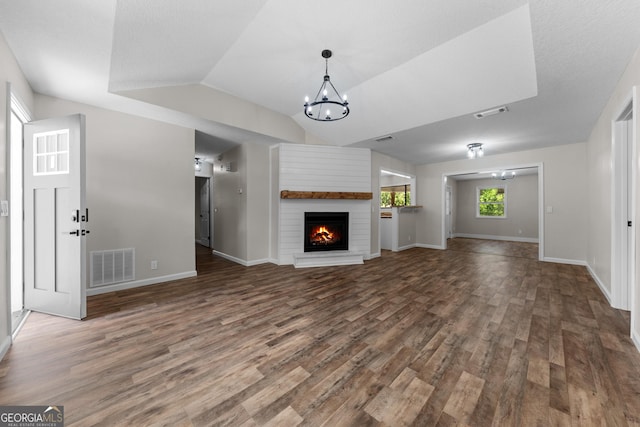 unfurnished living room with an inviting chandelier, wood finished floors, visible vents, and baseboards
