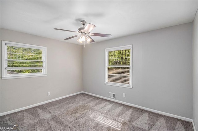 empty room featuring visible vents, a healthy amount of sunlight, and carpet
