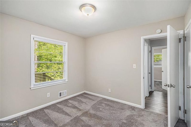 empty room featuring baseboards, visible vents, and carpet