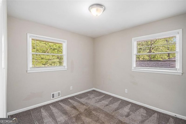 carpeted spare room featuring baseboards and visible vents