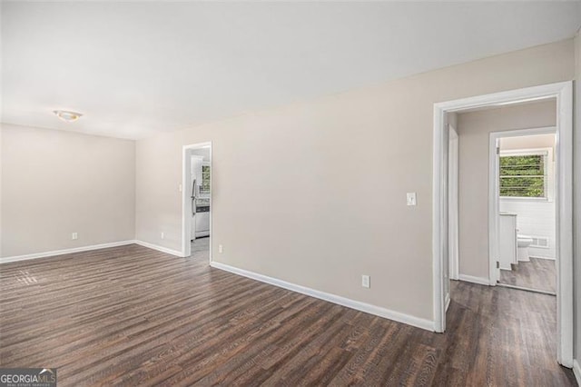 unfurnished room with dark wood finished floors and baseboards