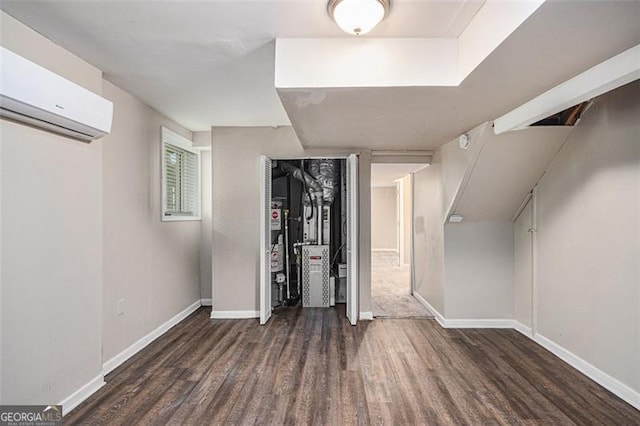 interior space with a wall unit AC, wood finished floors, and baseboards