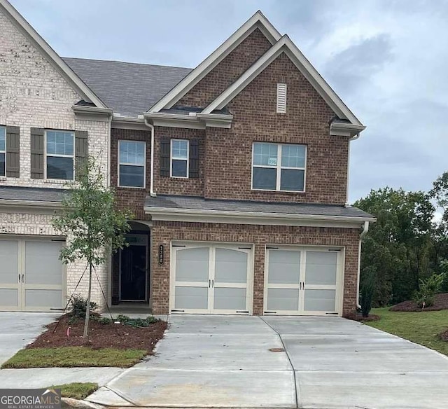 view of front of house with a garage, brick siding, a shingled roof, and concrete driveway