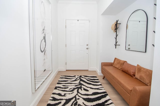 living area with baseboards, ornamental molding, and light wood-style flooring