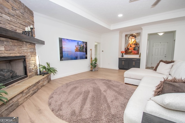 living area with baseboards, wood finished floors, crown molding, and a fireplace