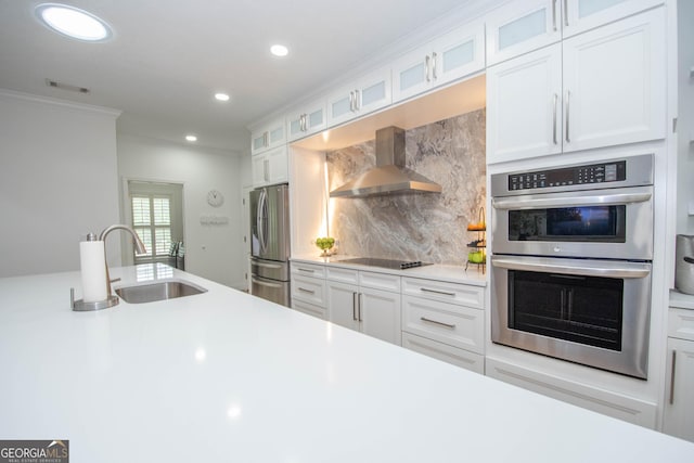 kitchen featuring wall chimney exhaust hood, appliances with stainless steel finishes, light countertops, and a sink