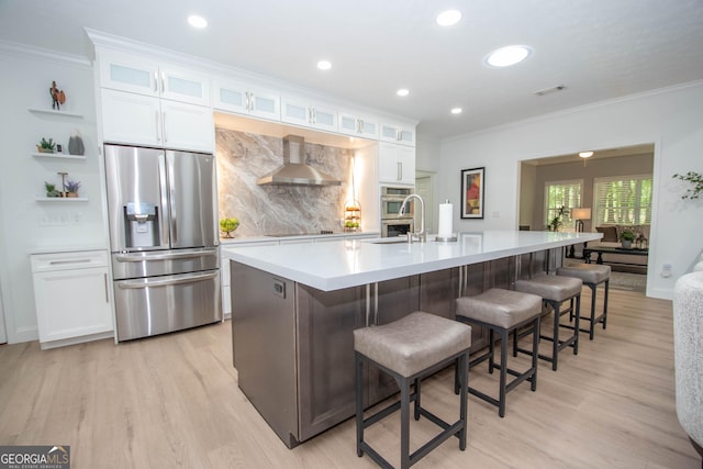 kitchen with wall chimney exhaust hood, stainless steel fridge, visible vents, and ornamental molding