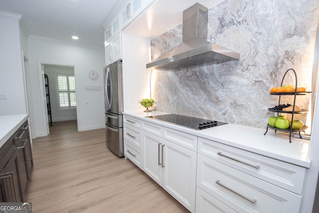 kitchen with black electric stovetop, exhaust hood, freestanding refrigerator, backsplash, and crown molding