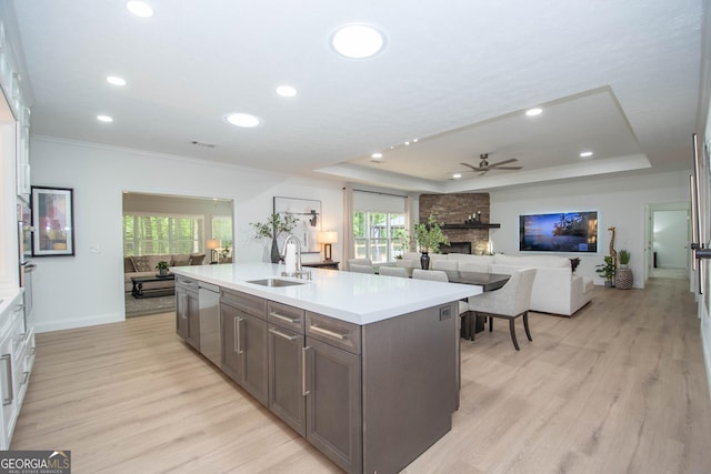 kitchen with open floor plan, light countertops, a tray ceiling, and a sink