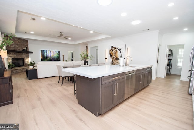 kitchen with stainless steel dishwasher, a kitchen island with sink, light wood-style floors, light countertops, and visible vents