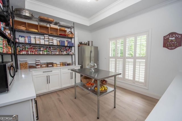 kitchen with white cabinetry, crown molding, appliances with stainless steel finishes, light countertops, and light wood finished floors