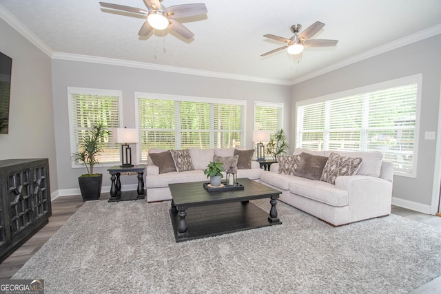 living area with wood finished floors, a ceiling fan, crown molding, and baseboards