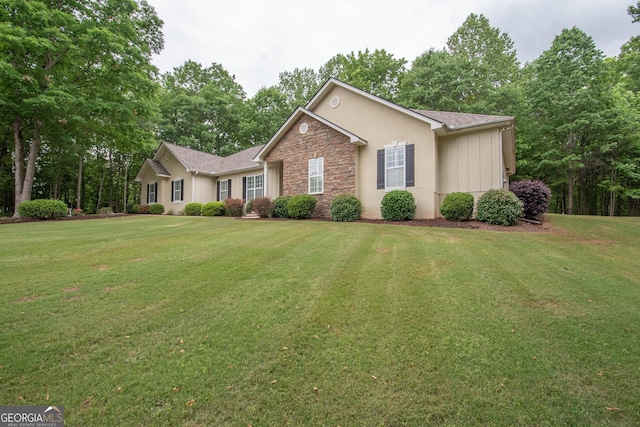 ranch-style house with a front lawn, stone siding, and stucco siding