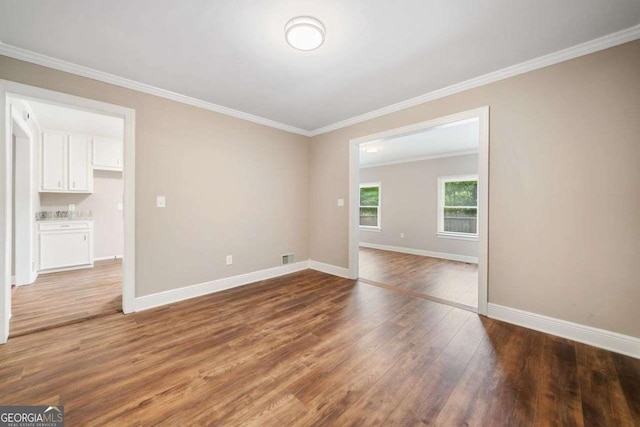 unfurnished room with ornamental molding, wood finished floors, and baseboards