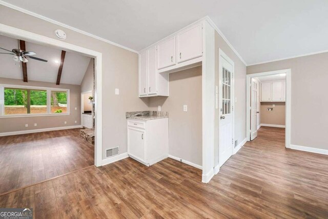 kitchen with ornamental molding, open floor plan, wood finished floors, and baseboards