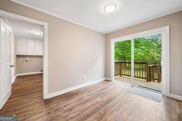 empty room with wood finished floors, crown molding, and baseboards