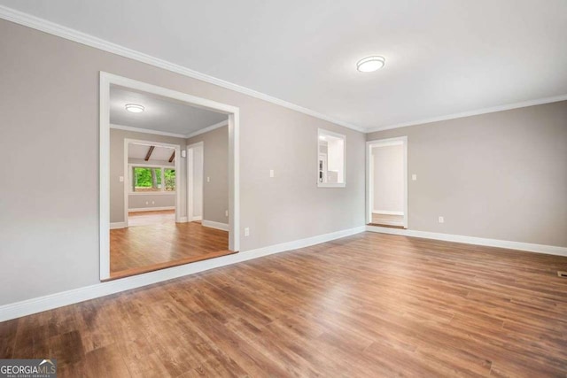unfurnished room featuring wood finished floors, ornamental molding, and baseboards
