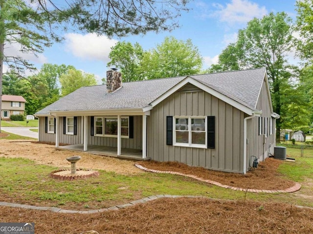 back of property featuring a porch, a shingled roof, central AC unit, board and batten siding, and a chimney