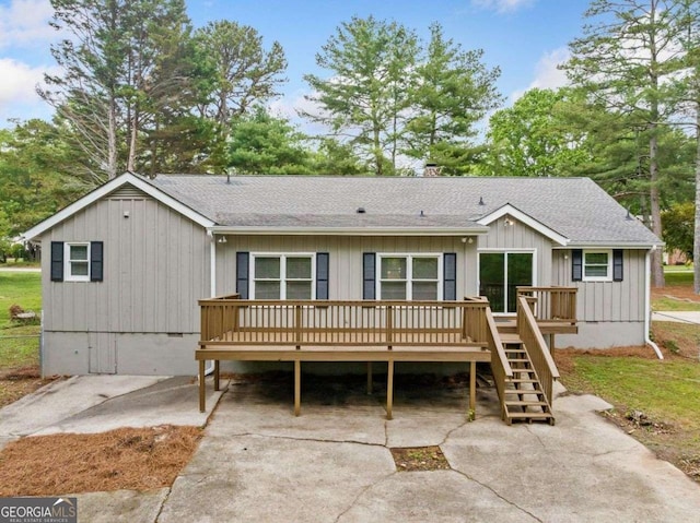 rear view of house featuring roof with shingles, a deck, and a chimney