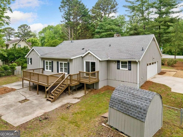 back of property with a chimney, fence, a shingled roof, a wooden deck, and a patio area