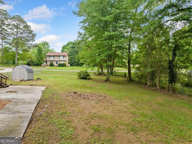 view of yard with fence, a storage unit, and an outbuilding