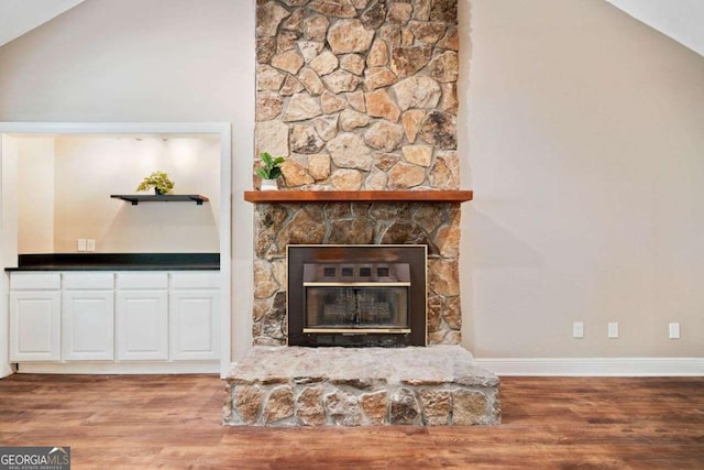 living room featuring a fireplace, wood finished floors, vaulted ceiling, and baseboards