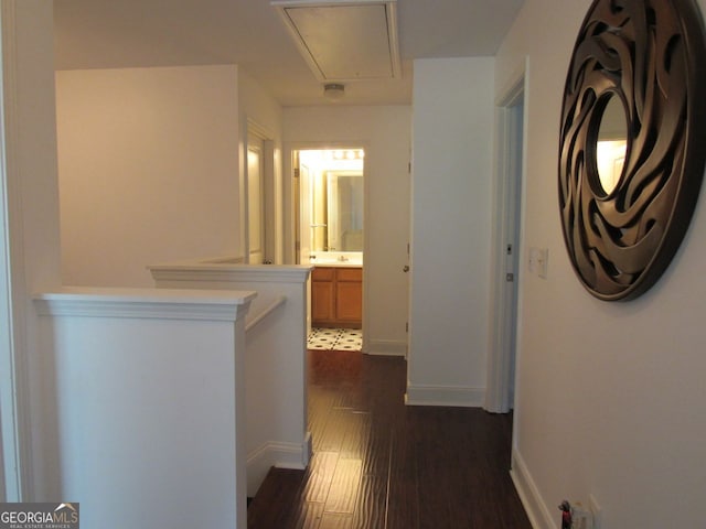 hallway with baseboards, attic access, and dark wood-type flooring