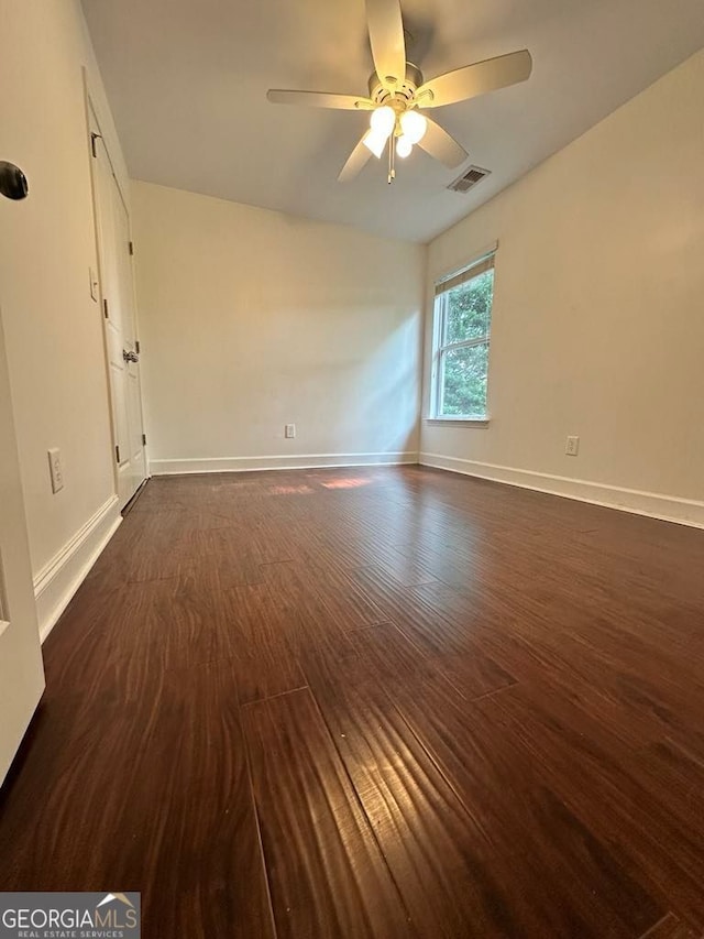 empty room with ceiling fan, visible vents, baseboards, and dark wood-type flooring