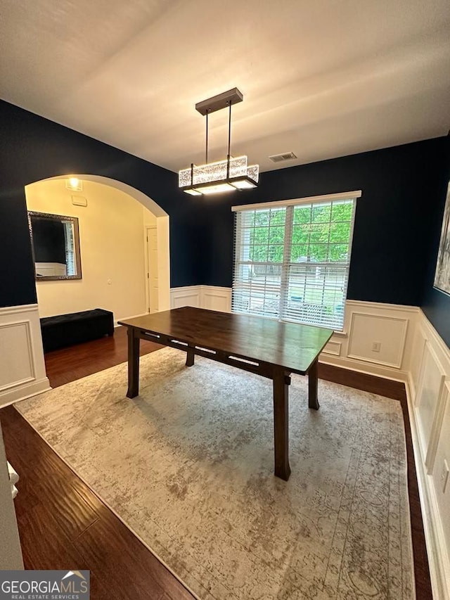playroom with a wainscoted wall, a decorative wall, arched walkways, and wood finished floors