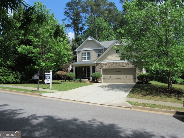 craftsman-style home featuring a front yard, driveway, an attached garage, and stone siding