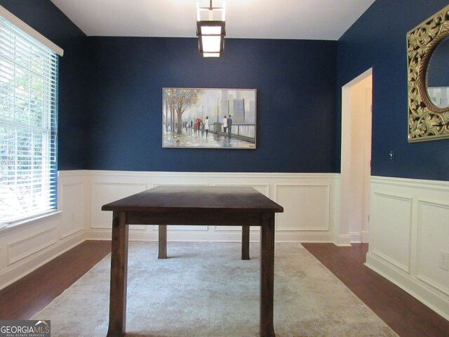 dining area with a wainscoted wall, a decorative wall, and wood finished floors