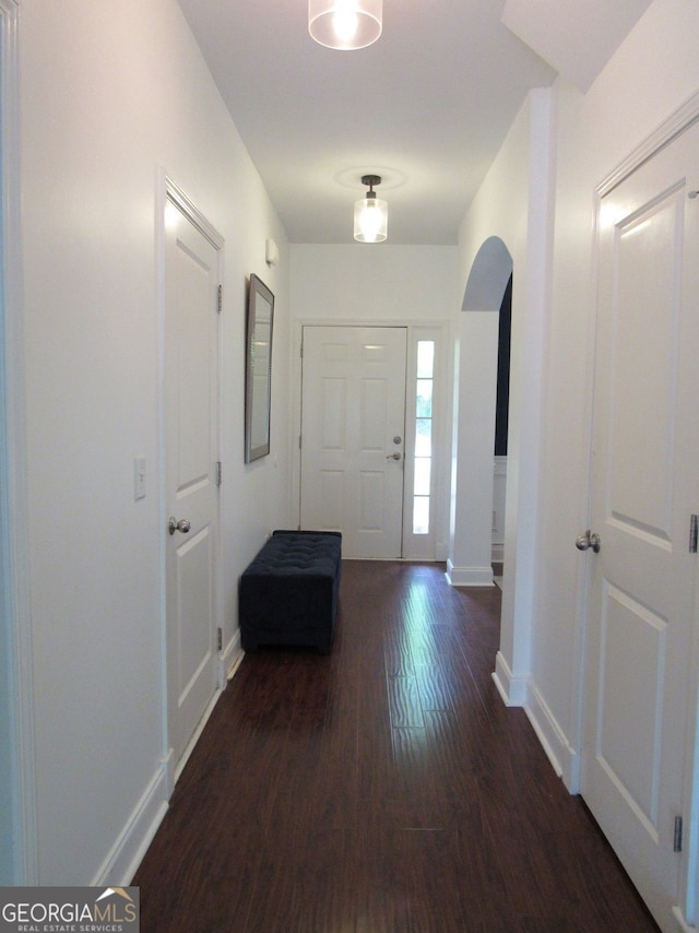 entrance foyer with arched walkways, baseboards, and wood finished floors