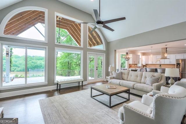 living room with vaulted ceiling, a wealth of natural light, ceiling fan with notable chandelier, and wood finished floors