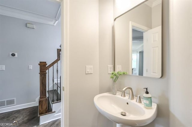 bathroom featuring visible vents, wood finished floors, a sink, baseboards, and ornamental molding