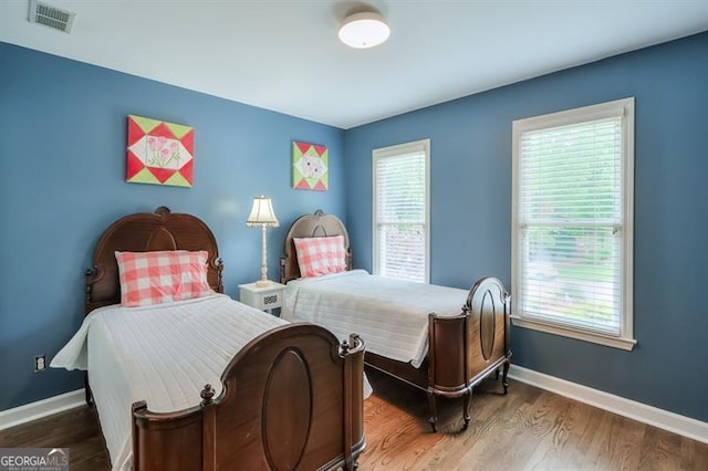 bedroom featuring baseboards, visible vents, and wood finished floors