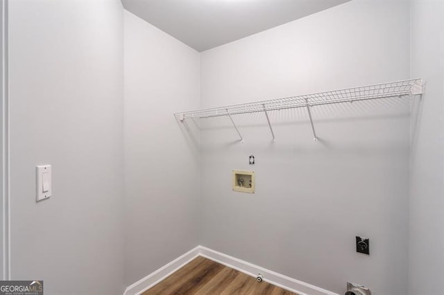 clothes washing area with washer hookup, hookup for an electric dryer, laundry area, wood finished floors, and baseboards