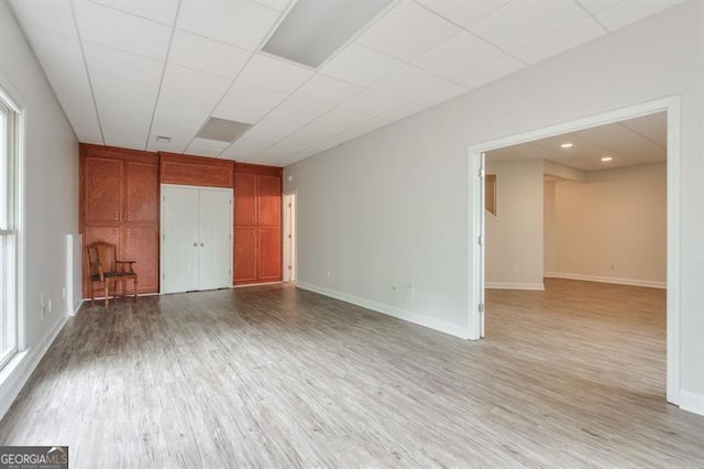 empty room featuring baseboards, wood finished floors, and a paneled ceiling