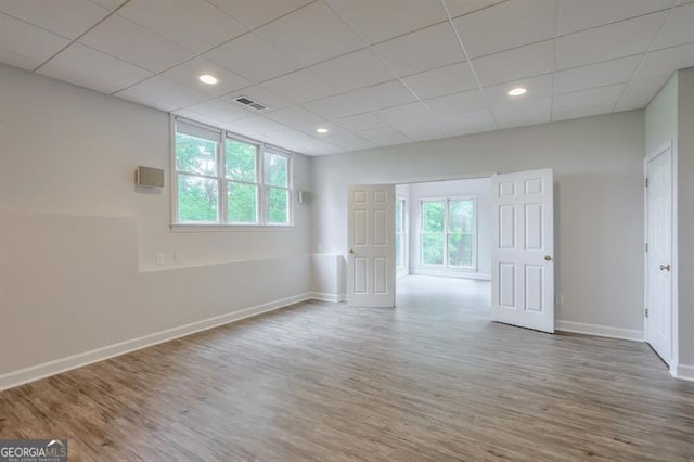 unfurnished room featuring baseboards, visible vents, a healthy amount of sunlight, and wood finished floors