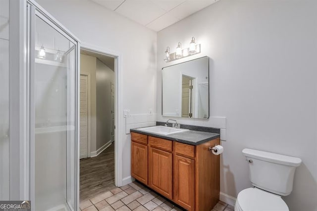 full bath featuring vanity, baseboards, a shower with door, and toilet