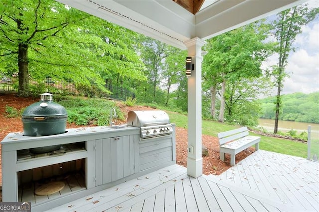 wooden deck with area for grilling, an outdoor kitchen, fence, and a sink