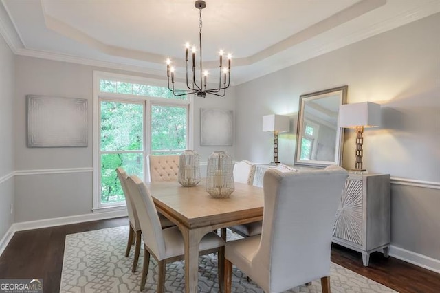dining space with a raised ceiling, dark wood-style flooring, and a chandelier