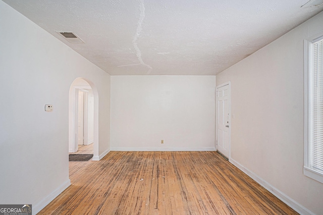 2447 Crestview Ave, Decatur, GA 30032 - empty room featuring arched walkways, wood-type flooring, baseboards, and a textured ceiling